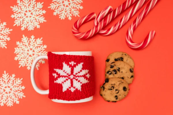 Top view of chocolate  cookies, candy canes, snowflakes and mug on red background — Stock Photo