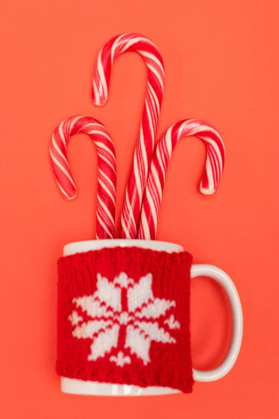 Vue de dessus des cannes de bonbons dans la tasse sur fond rouge — Photo de stock