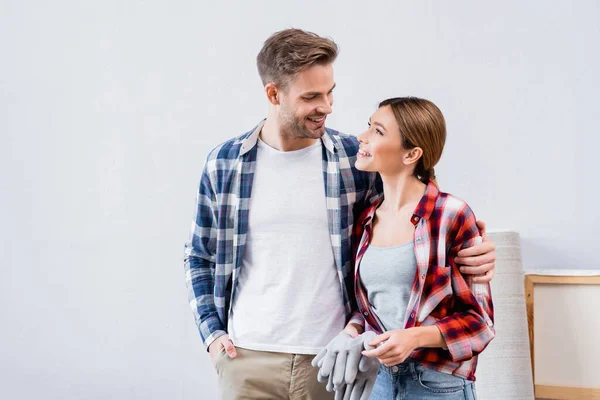 Sonriente joven pareja mirándose mientras se abrazan en casa - foto de stock