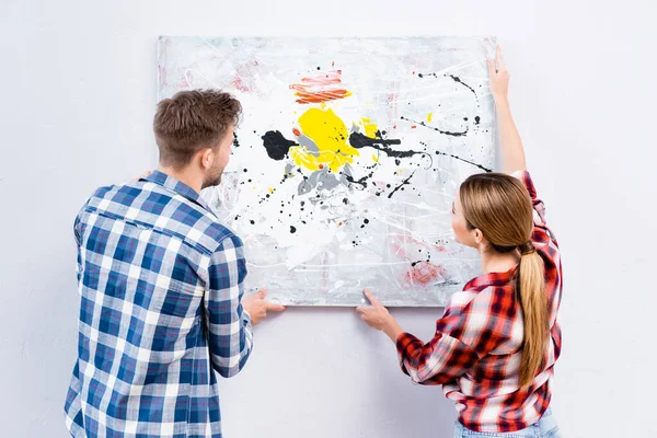 Back view of young couple removing picture from wall isolated on white — Stock Photo