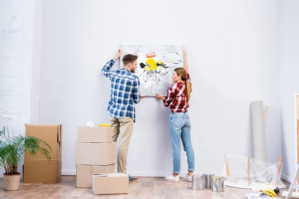 Longitud completa de sonriente joven pareja mirándose mientras se quita la foto en casa - foto de stock