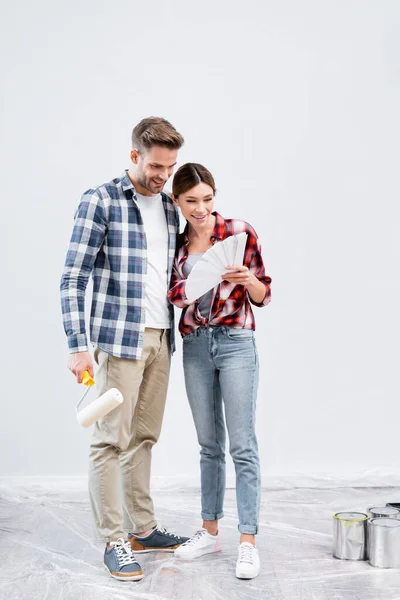 Pleine longueur de heureux jeune couple regardant la palette de couleurs à la maison — Photo de stock