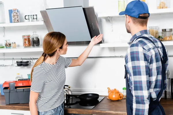 Jovem apontando com a mão em prateleiras perto de faz-tudo na cozinha — Fotografia de Stock