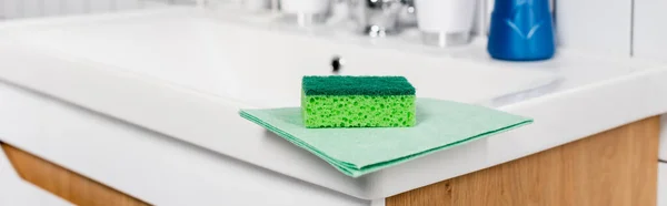 Зеленая губка и тряпка на раковине в ванной комнате, баннер — стоковое фото