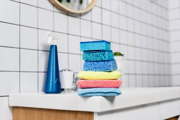 Colorful sponges on sink near detergent on blurred background in bathroom — Stock Photo