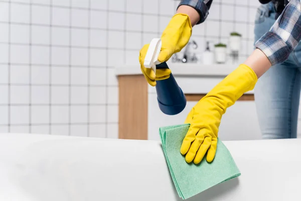 Vista ritagliata della donna in guanti di gomma pulizia vasca da bagno con detergente e straccio — Foto stock