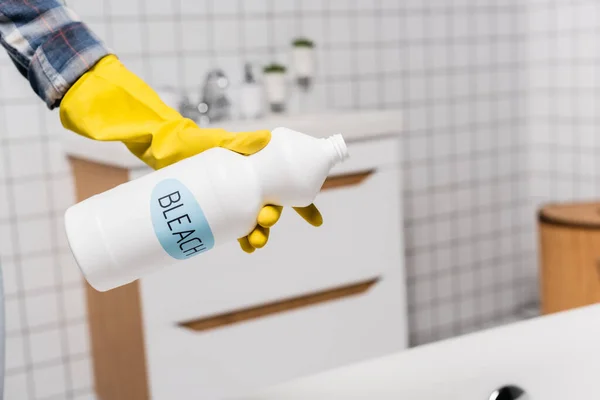 Vista recortada de la mujer sosteniendo la botella con letras de lejía en el baño - foto de stock