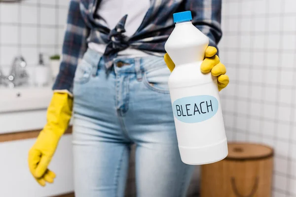 Bottle with bleach lettering in hand of woman in rubber glove on blurred background in bathroom — Stock Photo