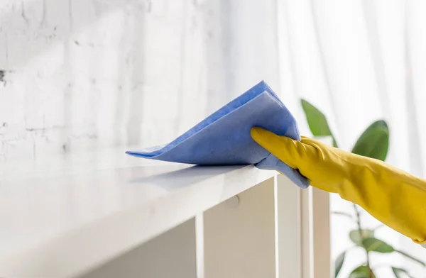 Ausgeschnittene Ansicht einer Person im Gummihandschuh-Schrank mit Lappen zu Hause — Stockfoto