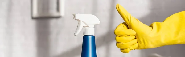 Vista recortada de la persona en guante de goma que muestra como gesto cerca de detergente con rociador, pancarta - foto de stock