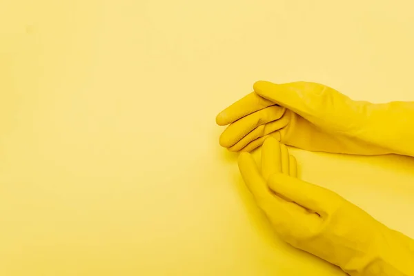 Vue du dessus des mains en gants de caoutchouc sur fond jaune — Photo de stock