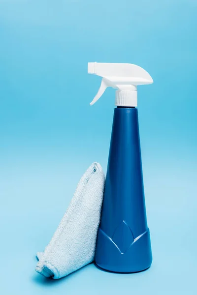 Rag and bottle of detergent on blue background — Stock Photo