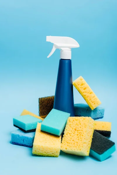 Flasche Waschmittel und Schwämme auf unscharfem Vordergrund auf blauem Hintergrund — Stockfoto