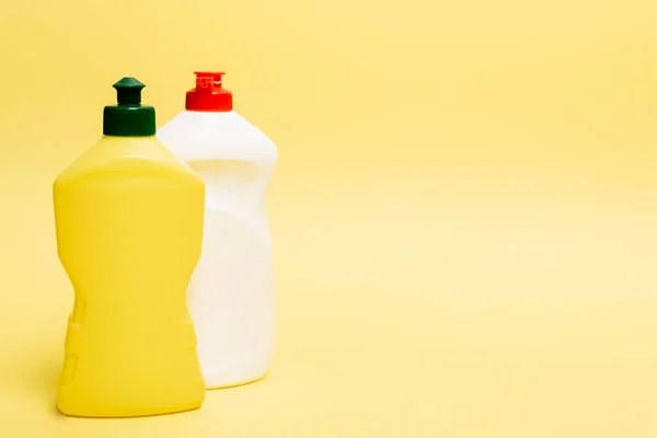 Bouteilles de liquide vaisselle sur fond jaune avec espace de copie — Photo de stock