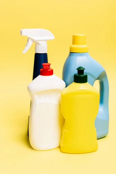 Пляшки посудомийної рідини та миючих засобів на жовтому фоні — стокове фото