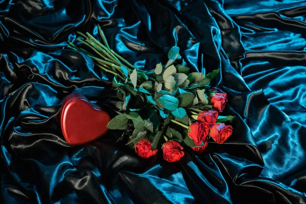 Draufsicht auf herzförmigen Kasten und Rosen auf schwarzem Bettzeug — Stockfoto