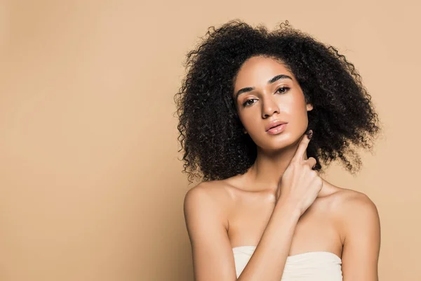 Young african american woman with bare shoulders looking at camera isolated on beige — Stock Photo