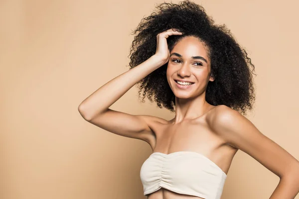 Cheerful african american woman with bare shoulders looking away isolated on beige — Stock Photo
