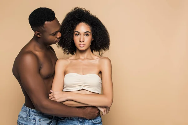 Afro americano homem abraçando encaracolado namorada com cruzados braços isolado no bege — Fotografia de Stock