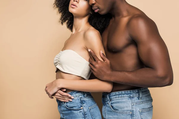 Visión parcial de la mujer afroamericana y el hombre abrazándose aislado en beige - foto de stock