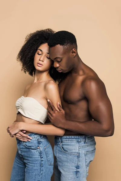 Shirtless african american man hugging woman with closed eyes isolated on beige — Stock Photo