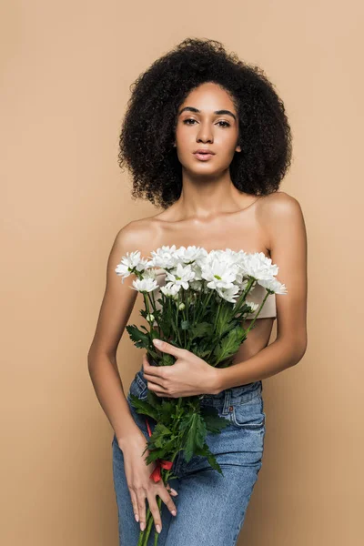 Encaracolado afro-americano mulher segurando flores isoladas no bege — Fotografia de Stock