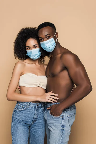 African american couple in medical masks looking at camera isolated on beige — Stock Photo