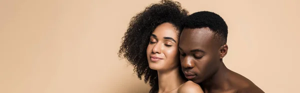 Uomo africano americano senza maglietta vicino compiaciuto fidanzata con spalle nude sul beige, banner — Foto stock