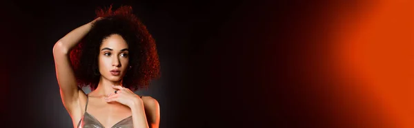 Curly african american woman fixing hair on black, banner — Stock Photo