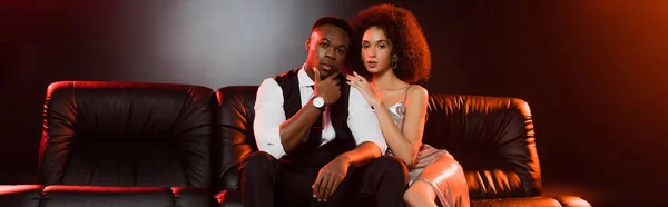 Elegante coppia afroamericana seduta sul divano nero, striscione — Foto stock
