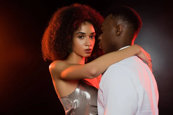 Красива афроамериканська жінка обіймає чоловіка на чорному — стокове фото