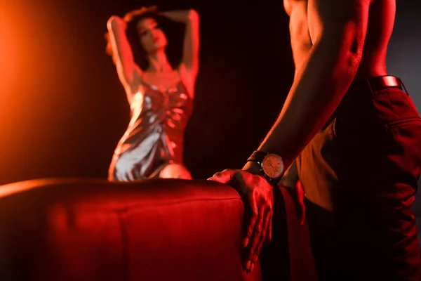 Shirtless african american man standing near couch and seductive woman on blurred background — Stock Photo