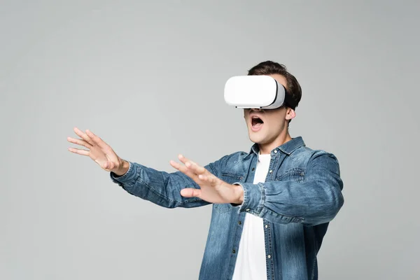 Hombre excitado usando auriculares vr aislados en gris - foto de stock