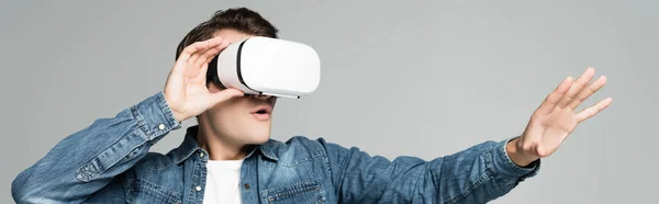 Joven hombre excitado usando auriculares vr aislados en gris, bandera - foto de stock