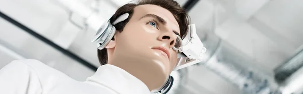 Low angle view of cyborg in headphones and digital eye lens looking away, banner — Stock Photo