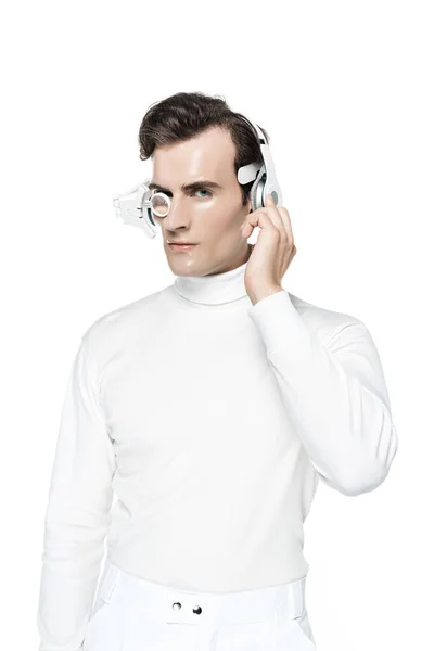 Cyborg en ropa blanca, lente de ojo digital y auriculares mirando a la cámara aislada en blanco - foto de stock