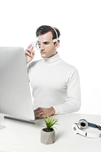 Cyborg en auriculares con ordenador cerca de los auriculares y la planta en primer plano borroso aislado en blanco - foto de stock