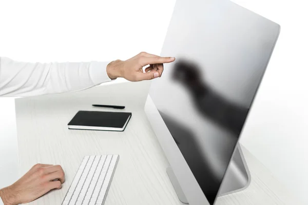 Cropped view of man pointing at computer with blank screen near notebook and pen on table isolated on white — Stock Photo