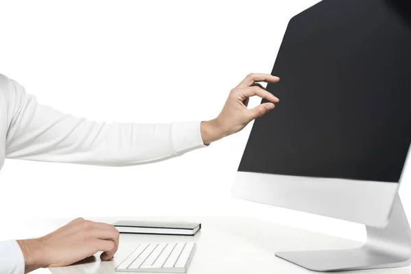 Vista recortada del hombre tocando la pantalla en blanco de la computadora cerca del cuaderno en la mesa aislada en blanco - foto de stock