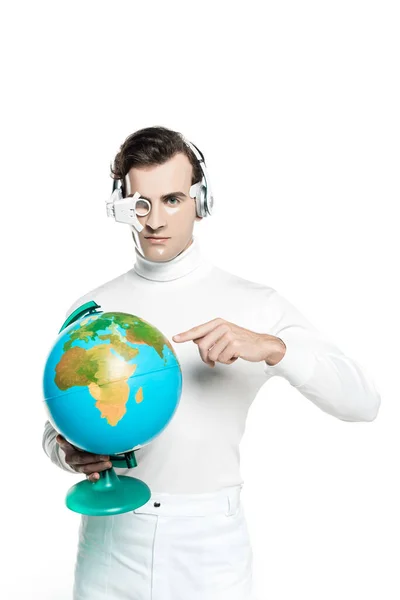 Cyborg in eye lens and headphones pointing at globe and looking at camera isolated on white — Stock Photo