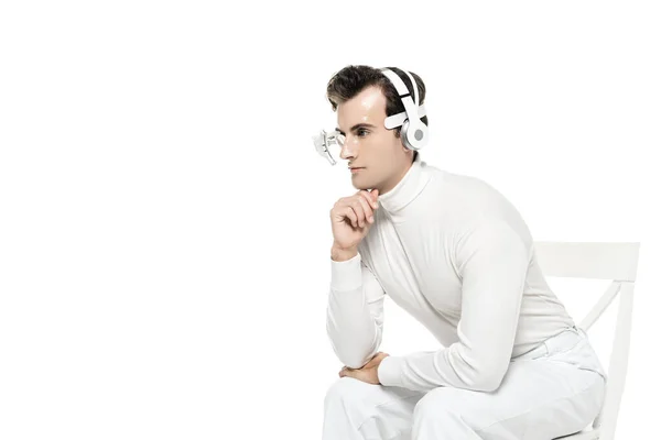 Кіборг в цифровій лінзі очей і навушники, що сидять на стільці ізольовані на білому — стокове фото