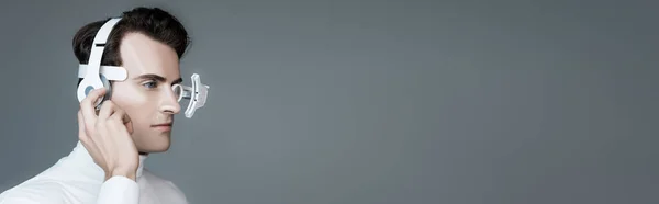 Cyborg in lente oculare digitale e mano vicino alle cuffie isolate su grigio, banner — Stock Photo