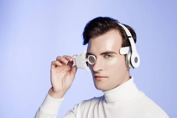 Cyborg in headphones and eye lens looking at camera isolated on blue — Stock Photo