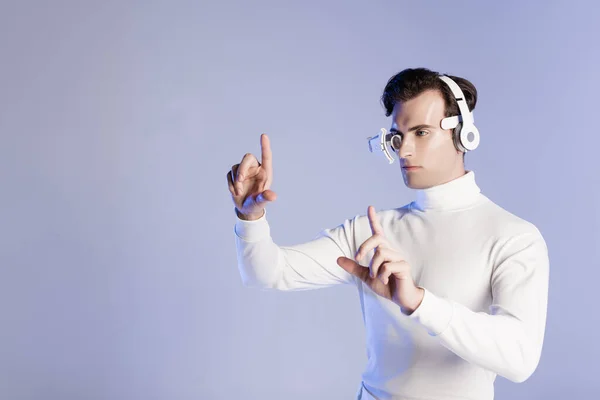 Cyborg man in headphones touching something isolated on purple — Stock Photo