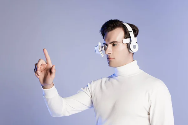 Cyborg en lente de ojo y auriculares tocando algo aislado en púrpura - foto de stock