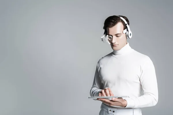 Cyborg man in headphones using computer keyboard isolated on grey with copy space — Stock Photo