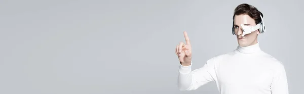 Cyborg em fones de ouvido apontando com o dedo isolado em cinza, banner — Fotografia de Stock