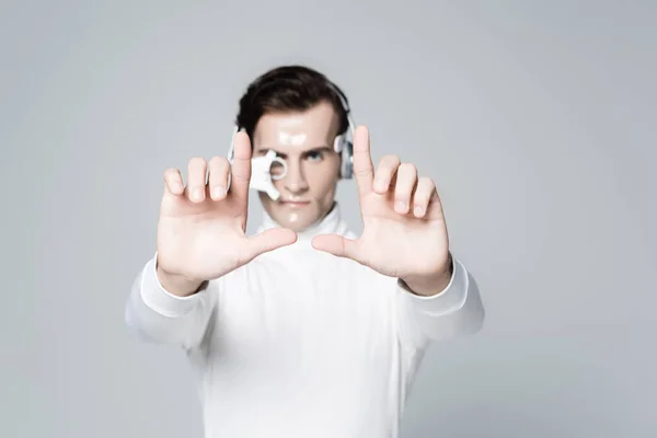 Cyborg man in headphones on blurred background touching something isolated on grey — Stock Photo