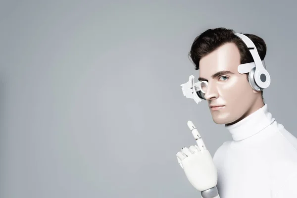 Cyborg uomo in cuffia con mano artificiale punta con dito isolato su grigio — Foto stock