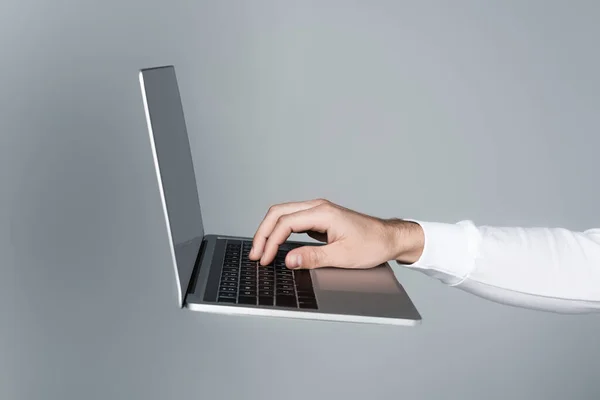 Cropped view of man using laptop with blank screen in air isolated on grey — Stock Photo